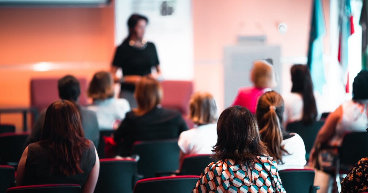 A woman representing sex therapist Andi Grushka speaking in front of an audience at a conference for sex therapists and sexual health